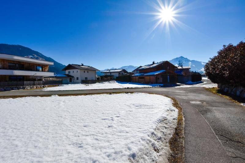 Weitläufiges Grundstück mit Schnee, umgeben von alpiner Architektur und einer klaren Berglandschaft.