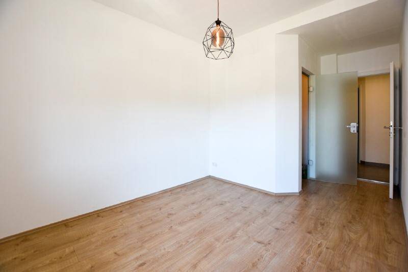 Leerer Raum mit Holzboden und moderner Pendelleuchte, bereit zur individuellen Gestaltung.