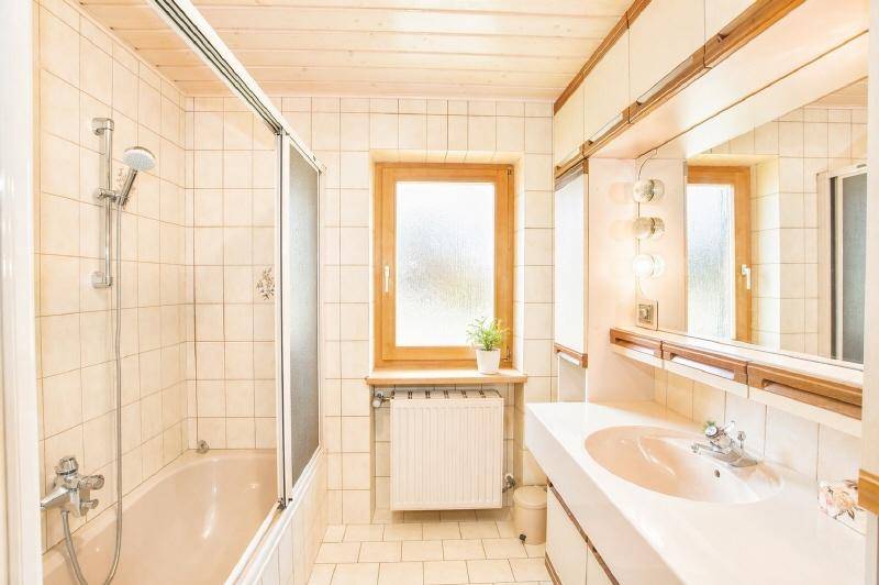 Helles Badezimmer mit Badewanne, Duschfunktion, Einzelwaschbecken und Fenster.