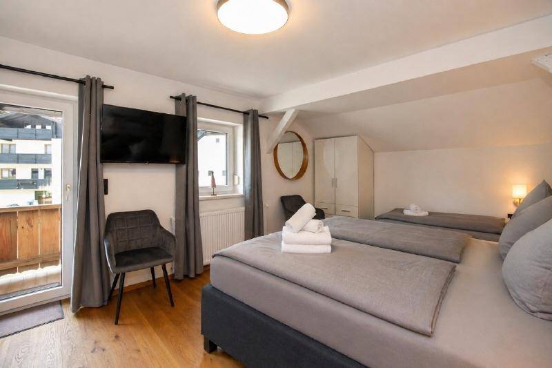 Helles Schlafzimmer mit Doppelbett, Holzboden und direktem Zugang zum Balkon.