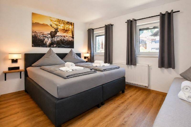 Komfortables Schlafzimmer mit Doppelbett, Holzboden und Hirschmotiv-Wandbild.