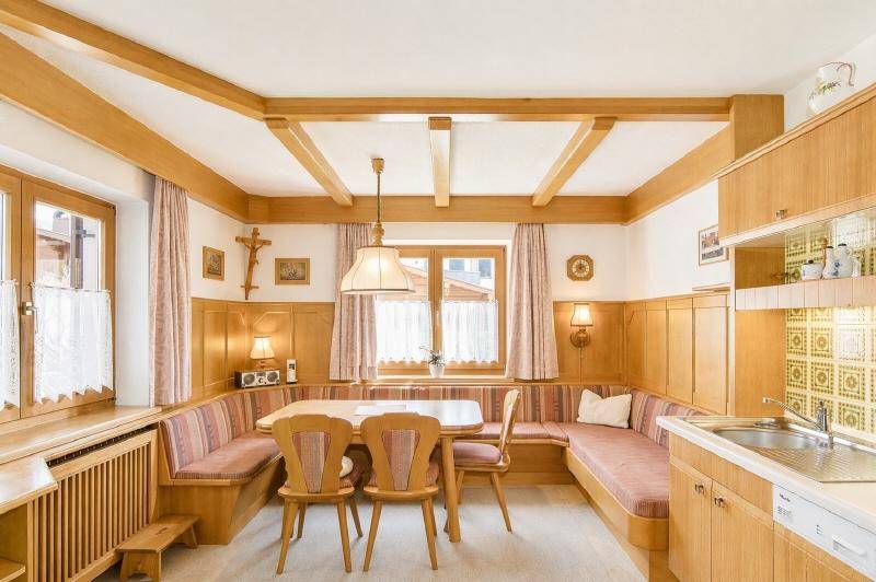 Gemütliche Wohnküche im alpenländischen Stil mit Holzbalken, Eckbank und integrierter Küchenzeile.