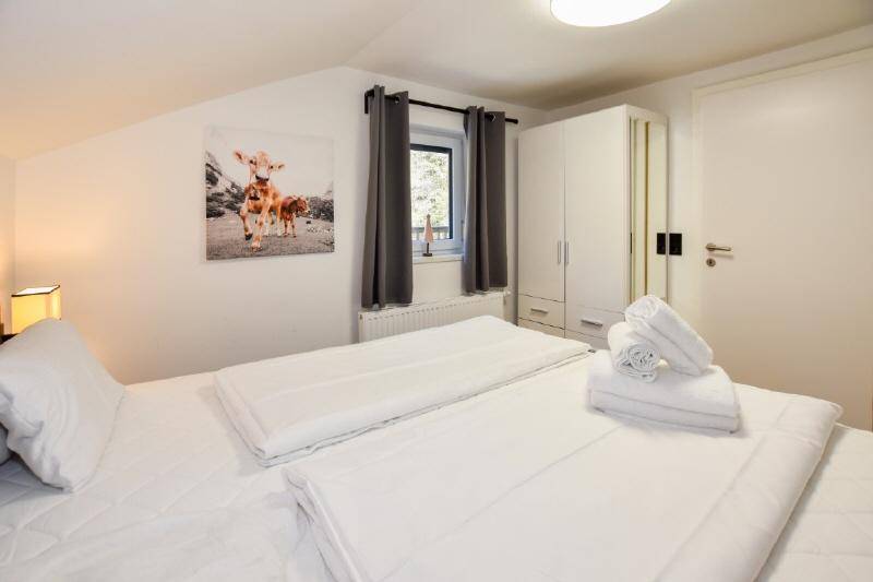 Gemütliches Schlafzimmer mit Doppelbett, Kleiderschrank und Dachschräge.