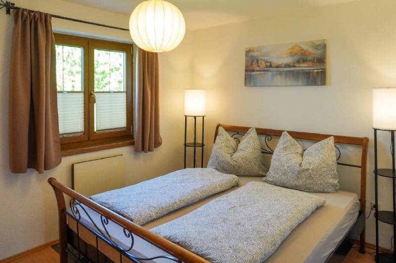 Gemütliches Schlafzimmer mit Doppelbett, Holzbettrahmen und warmem Licht.