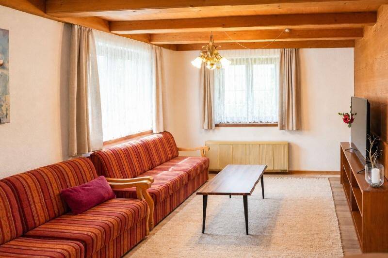 Gemütliches Wohnzimmer im Landhausstil mit sichtbaren Holzbalken und gestreiften Sofas.