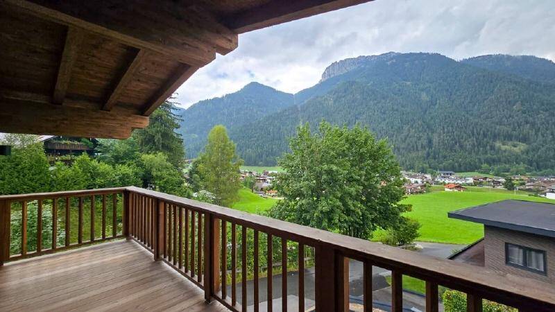 Geräumiger Holzbalkon mit atemberaubendem Blick auf die umliegenden Berge und grüne Täler.