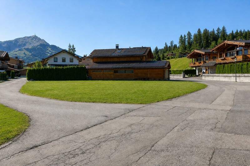 Gepflegte Rasenfläche umgeben von Wohnhäusern und einer malerischen Bergkulisse.