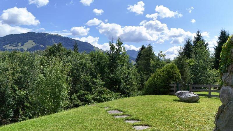 Idyllischer Blick vom Garten auf die umliegende Berglandschaft und grüne Wälder.