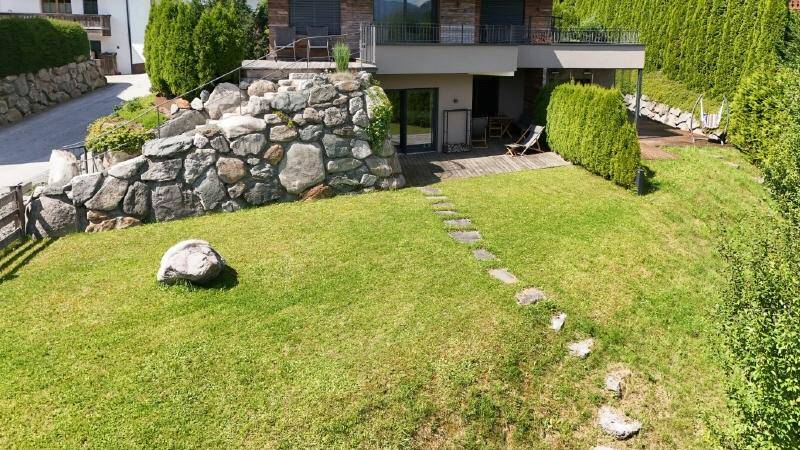 Gepflegter Rasenbereich mit Steinstufen und einer Terrasse am modernen Wohnhaus.
