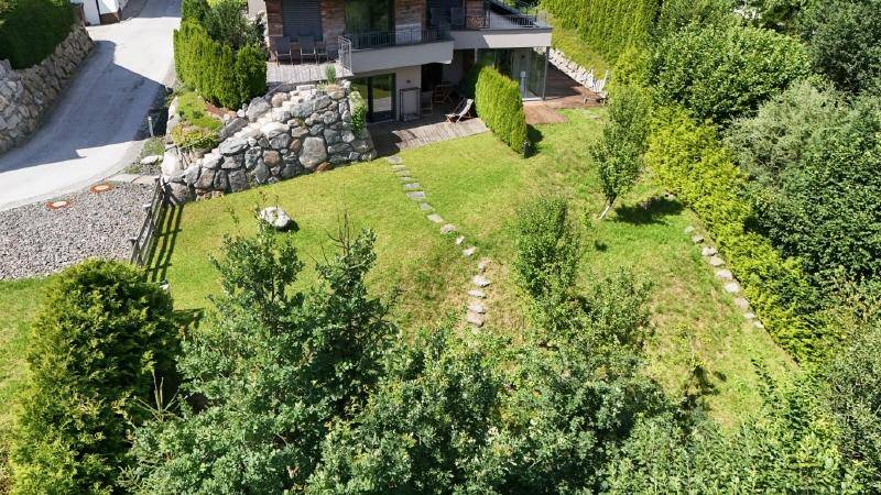 Luftaufnahme des modernen Hauses mit weitläufigem, grünem Garten und Baumbestand.