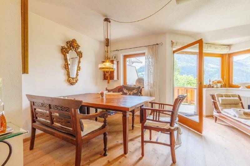 Gemütlicher Essbereich mit Holztisch, traditionellen Möbeln und Zugang zu einem Balkon mit Bergblick.