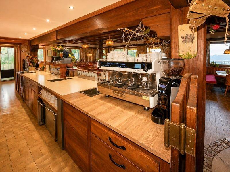 Rustikale Bar mit Holzelementen, einer professionellen Kaffeemaschine und gemütlicher Beleuchtung.