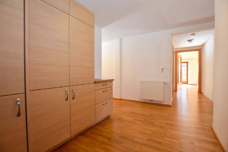 Langer Flur mit Holzboden, Heizkörper und Blick in angrenzende Zimmer.