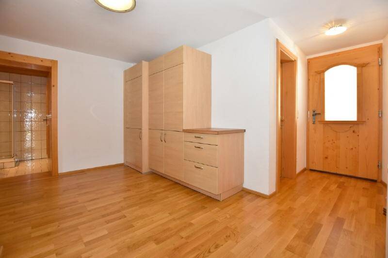 Eingangsbereich mit Holzschrank, Holzboden und Zugang zu weiteren Räumen.