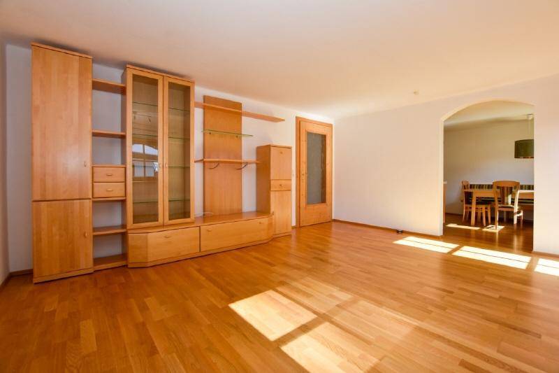 Helles Wohnzimmer mit Holzparkettboden und einem Durchgang zum Essbereich.