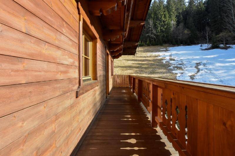 Langer Holzbalkon mit traditionellem Geländer und Blick auf die Natur.