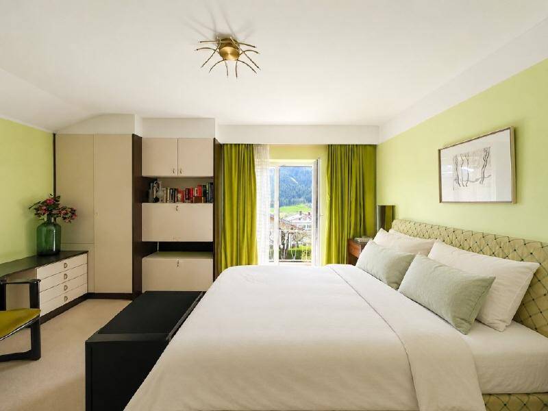 Helles Schlafzimmer mit grünen Wänden, Doppelbett und Zugang zu einem Balkon mit Bergblick.