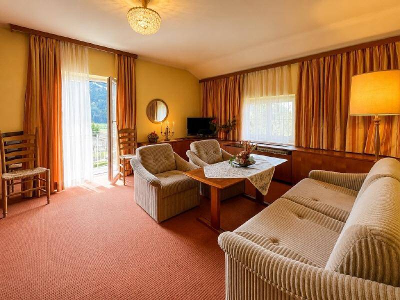 Gemütliches Wohnzimmer mit gestreiften Sesseln, Sofa und Zugang zu einem Außenbereich.