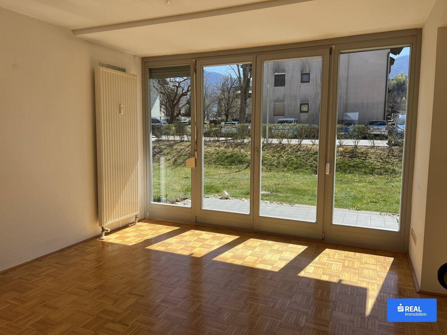 Helles Wohnzimmer mit Parkettboden und großen Fenstern zum Gartenbereich.