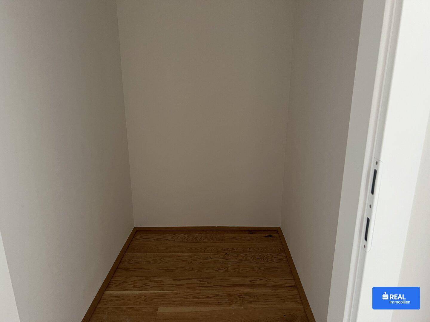 Kleiner, leerer Raum mit Holzboden, ideal als Abstellraum oder begehbarer Kleiderschrank.
