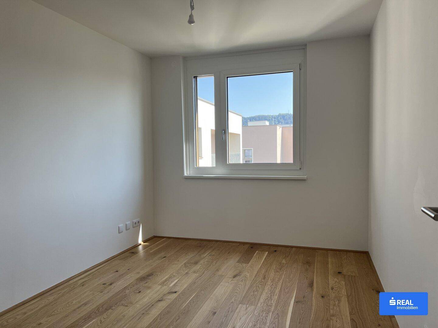 Weiteres helles Zimmer mit Holzboden und einem Fenster, ideal als Schlaf- oder Arbeitszimmer.