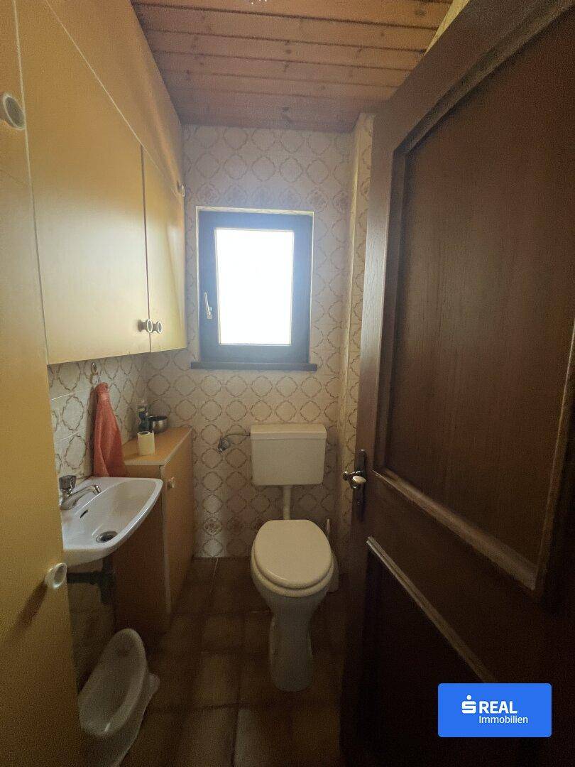 Kleines Gäste-WC mit Fenster, Waschbecken und Holzdecke im traditionellen Stil.