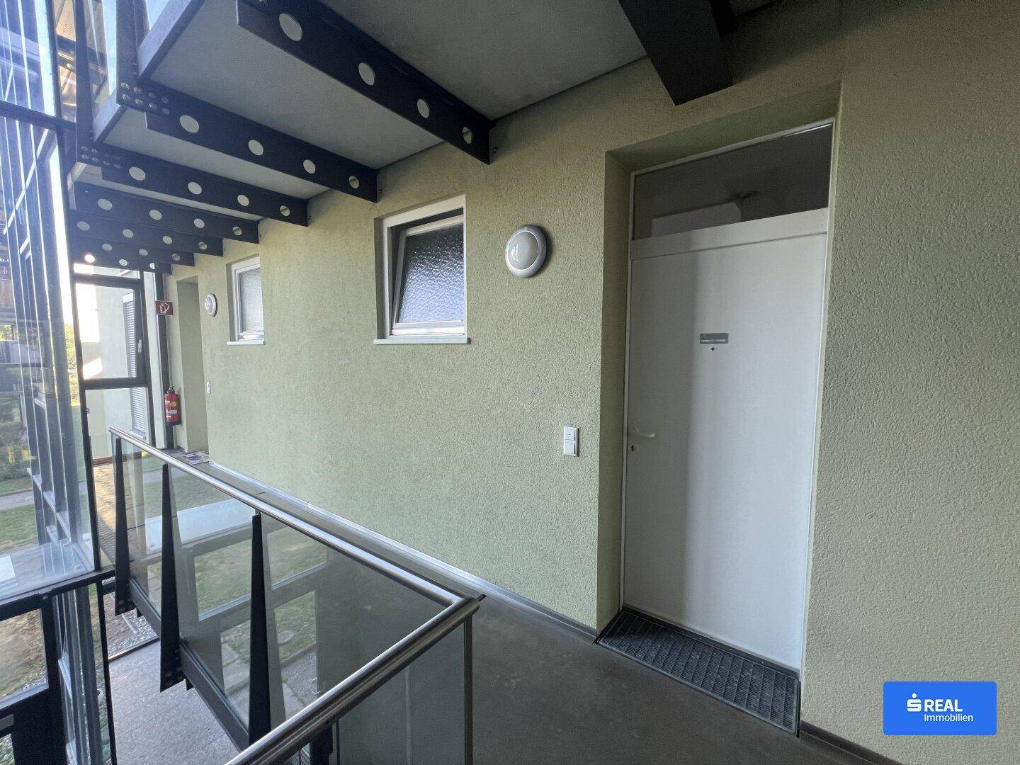 Heller Flur im Treppenhaus mit Zugang zu den Wohnungen und einem Fenster, das Tageslicht hereinlässt.