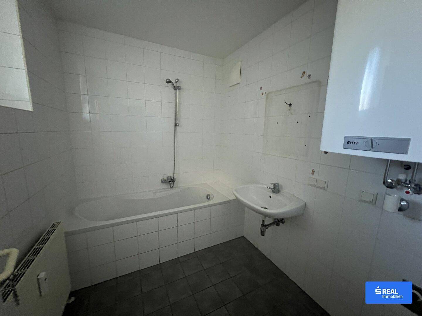 Badezimmer mit Badewanne, Waschbecken und weißen Fliesen, funktional und hell gestaltet.