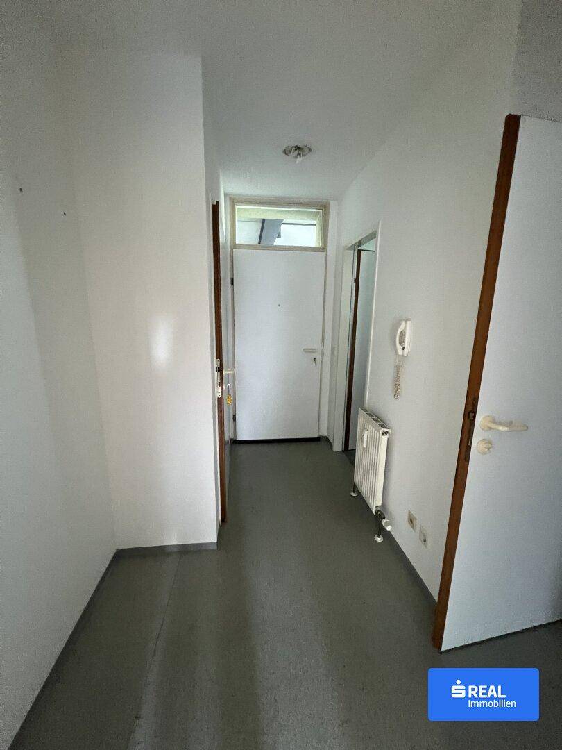 Heller Flur im Inneren der Wohnung mit weiß gestrichenen Wänden und Holztüren, einladend und sauber.