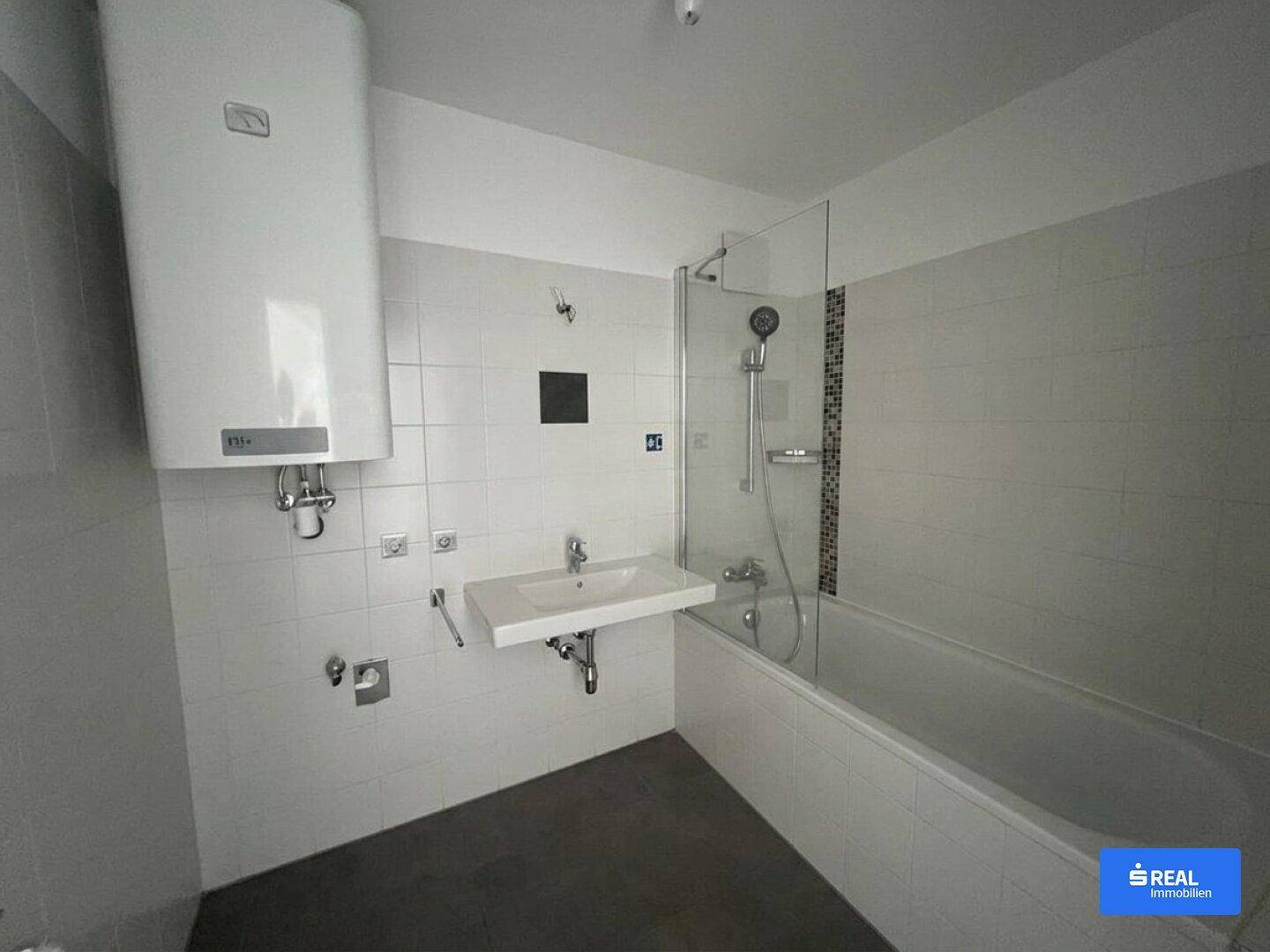 Badezimmer mit Badewanne, Duschbereich und Waschbecken in hellen Fliesen.