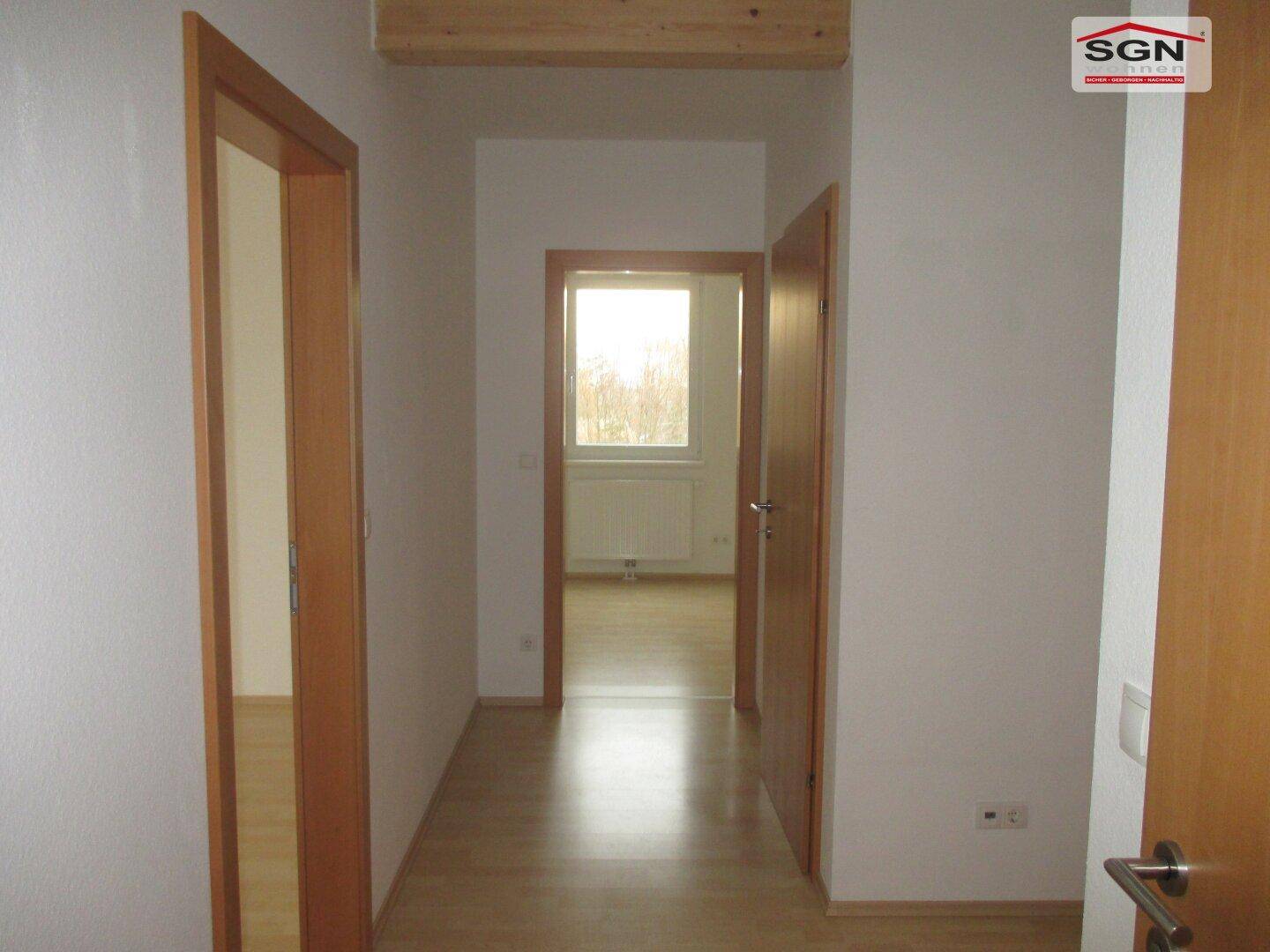 Heller Flur mit Laminatboden und mehreren Türen zu angrenzenden Räumen.
