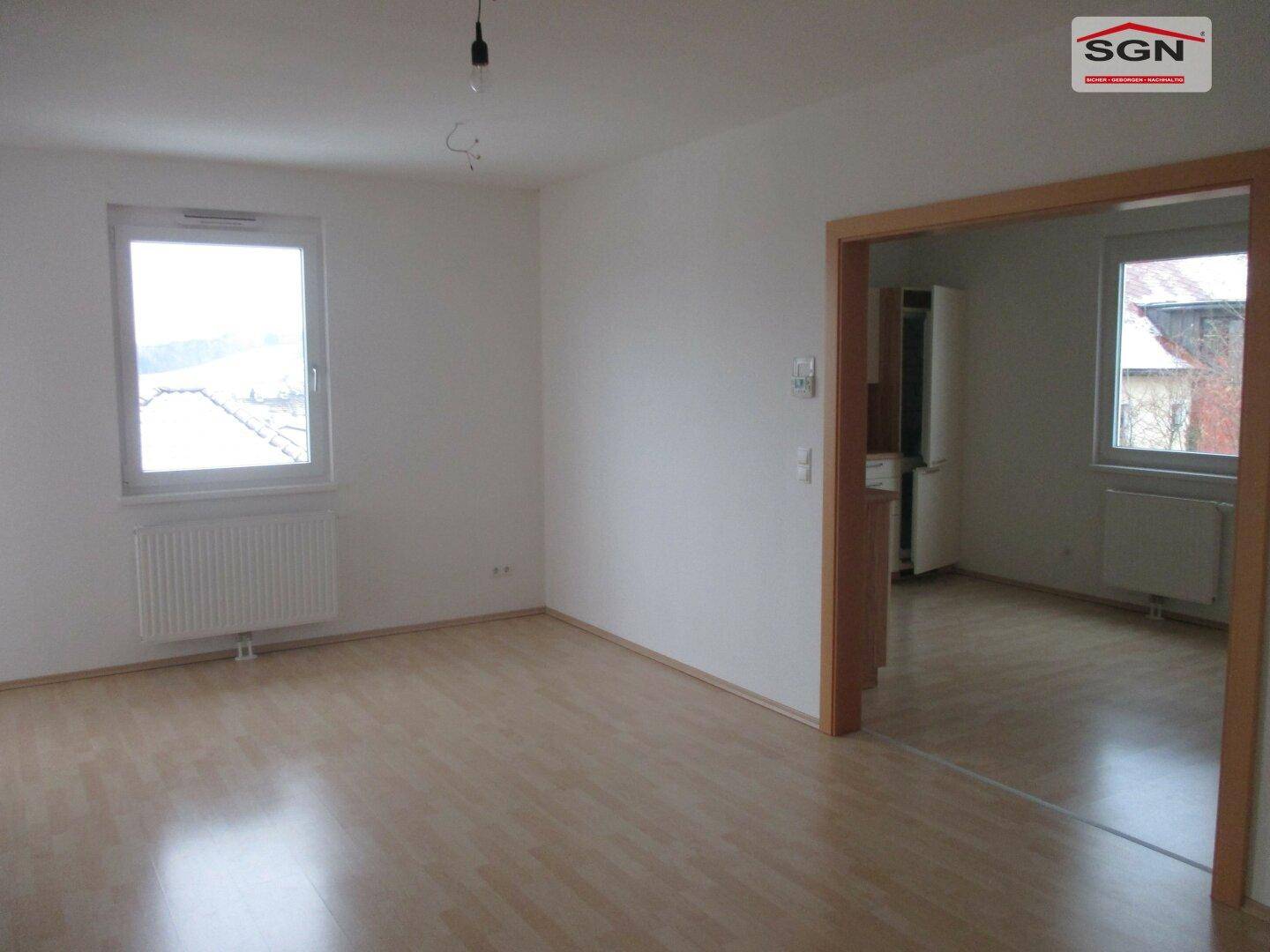 Heller, leerer Raum mit Laminatboden und Zugang zu einem weiteren Zimmer.