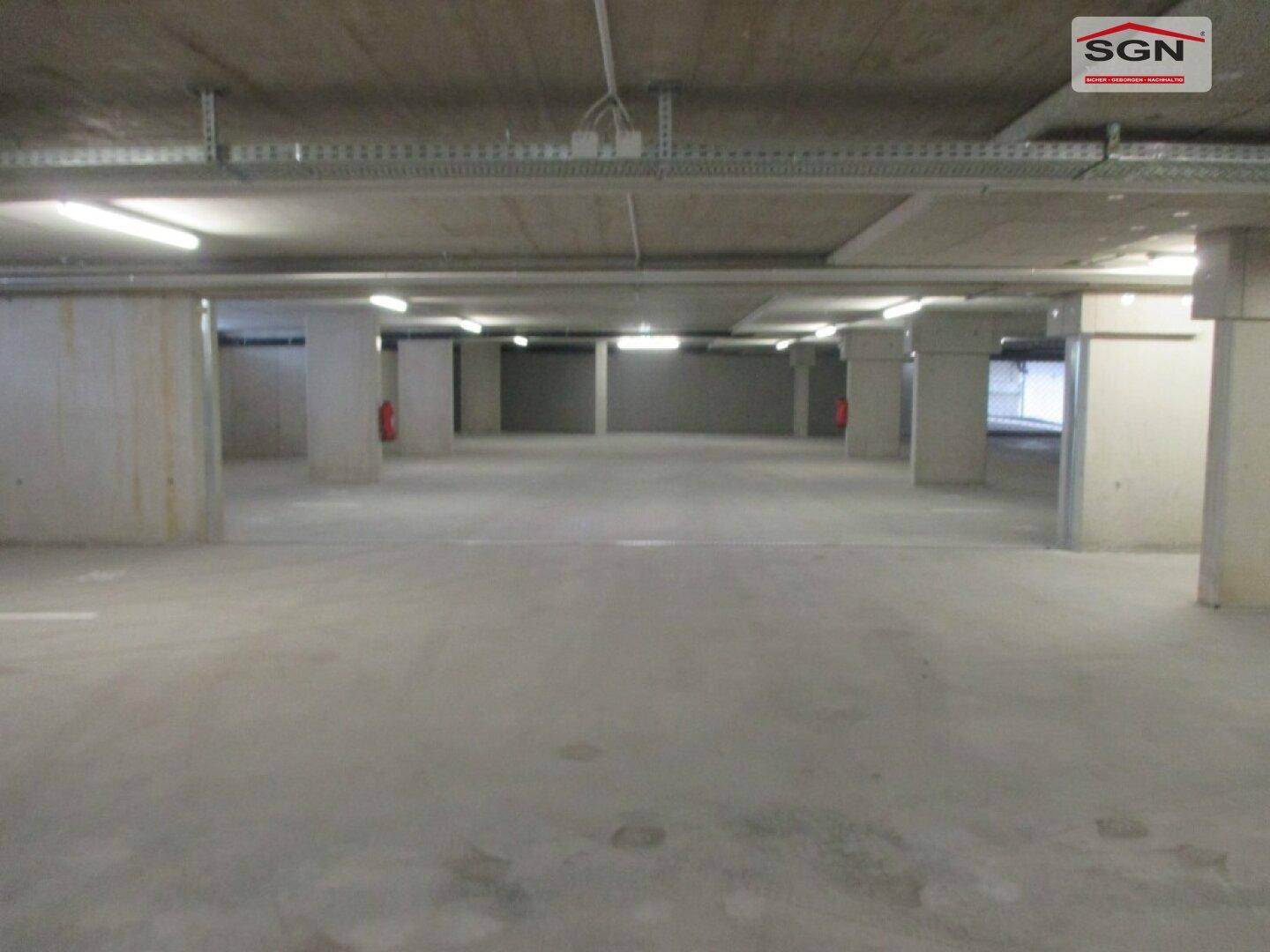 Geräumige Tiefgarage mit Betonwänden und Decken, gut beleuchtet.