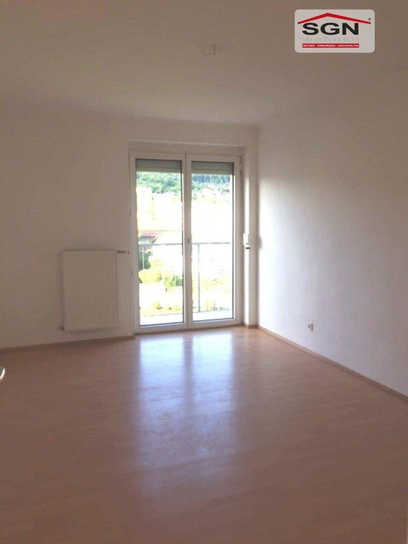 Heller Raum mit Laminatboden und Zugang zu einem französischen Balkon, ideal für frische Luft.