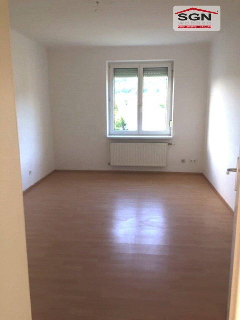 Freundlicher, leerer Raum mit Laminatboden und Fenster, bietet viel Tageslicht und Gestaltungsmöglichkeiten.