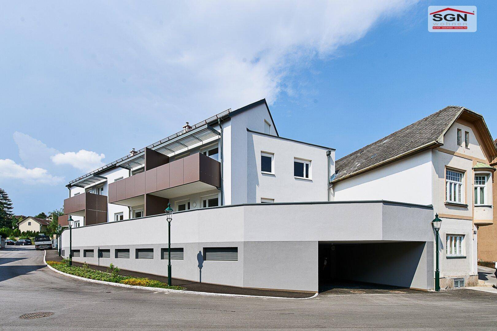 Moderne Wohnanlage mit integriertem Carport und weißer Fassade an einer Straße.
