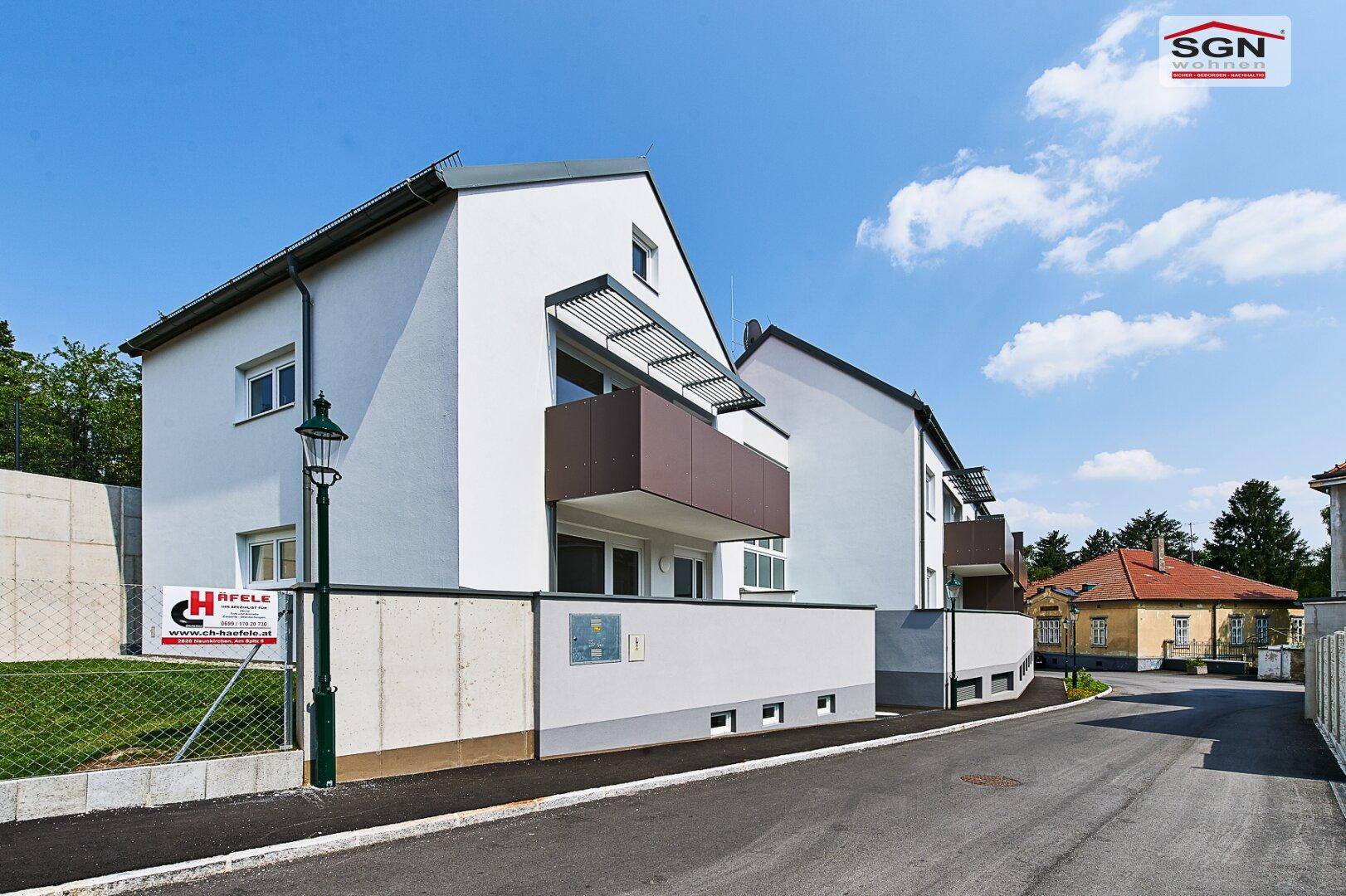 Neubau-Wohngebäude mit klaren Linien und Balkonen in sonniger Umgebung.