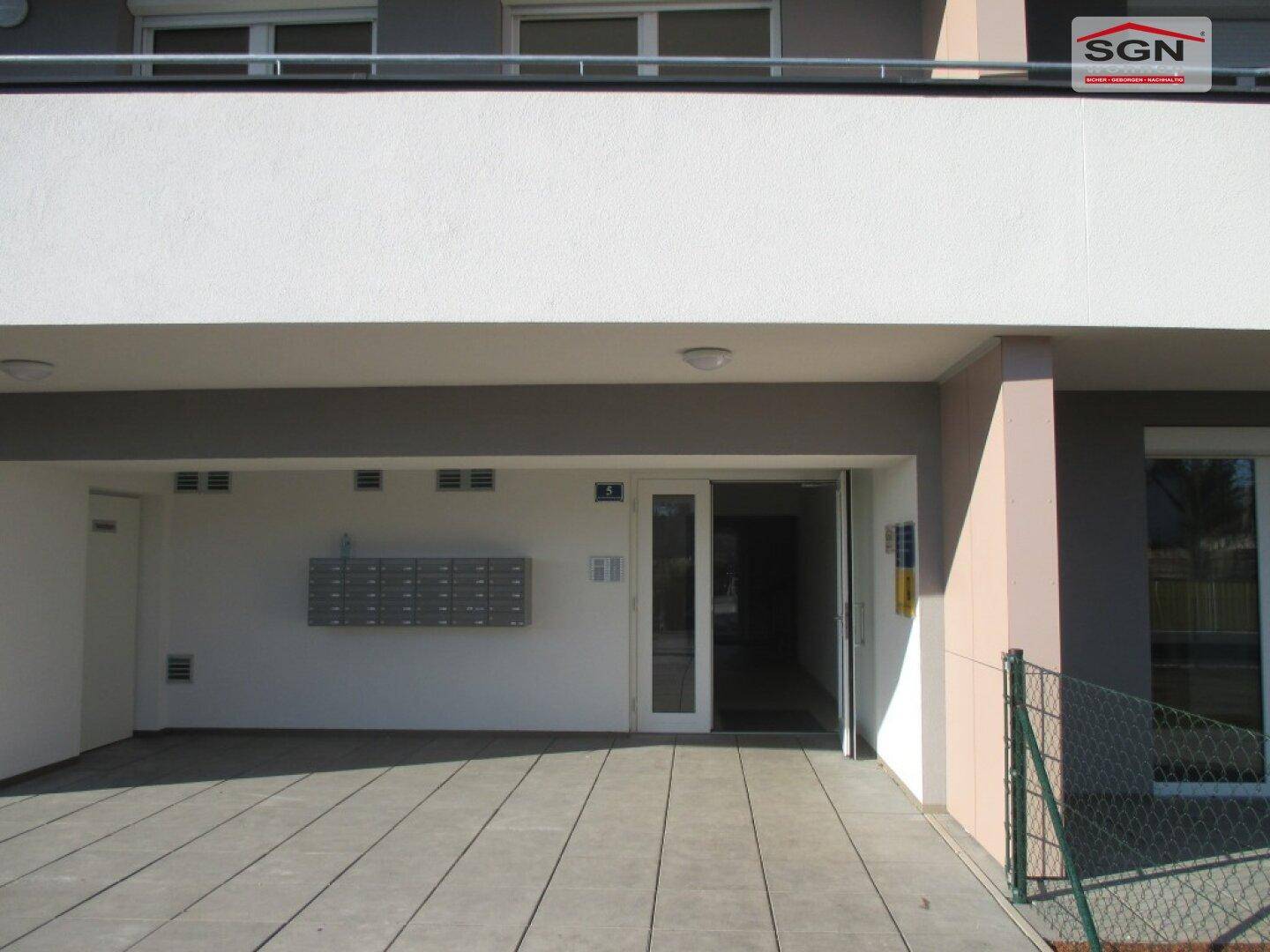 Eingangsbereich eines modernen Wohngebäudes mit Briefkästen und gefliestem Zugang.