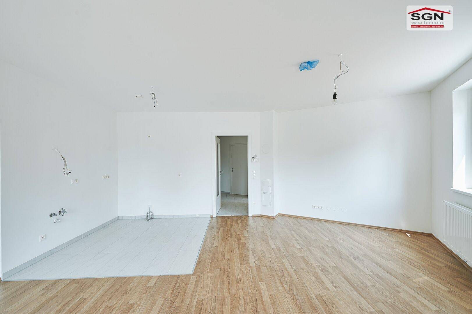 Heller, unmöblierter Raum mit Holzboden und Fliesenbereich, bereit zum Einzug.