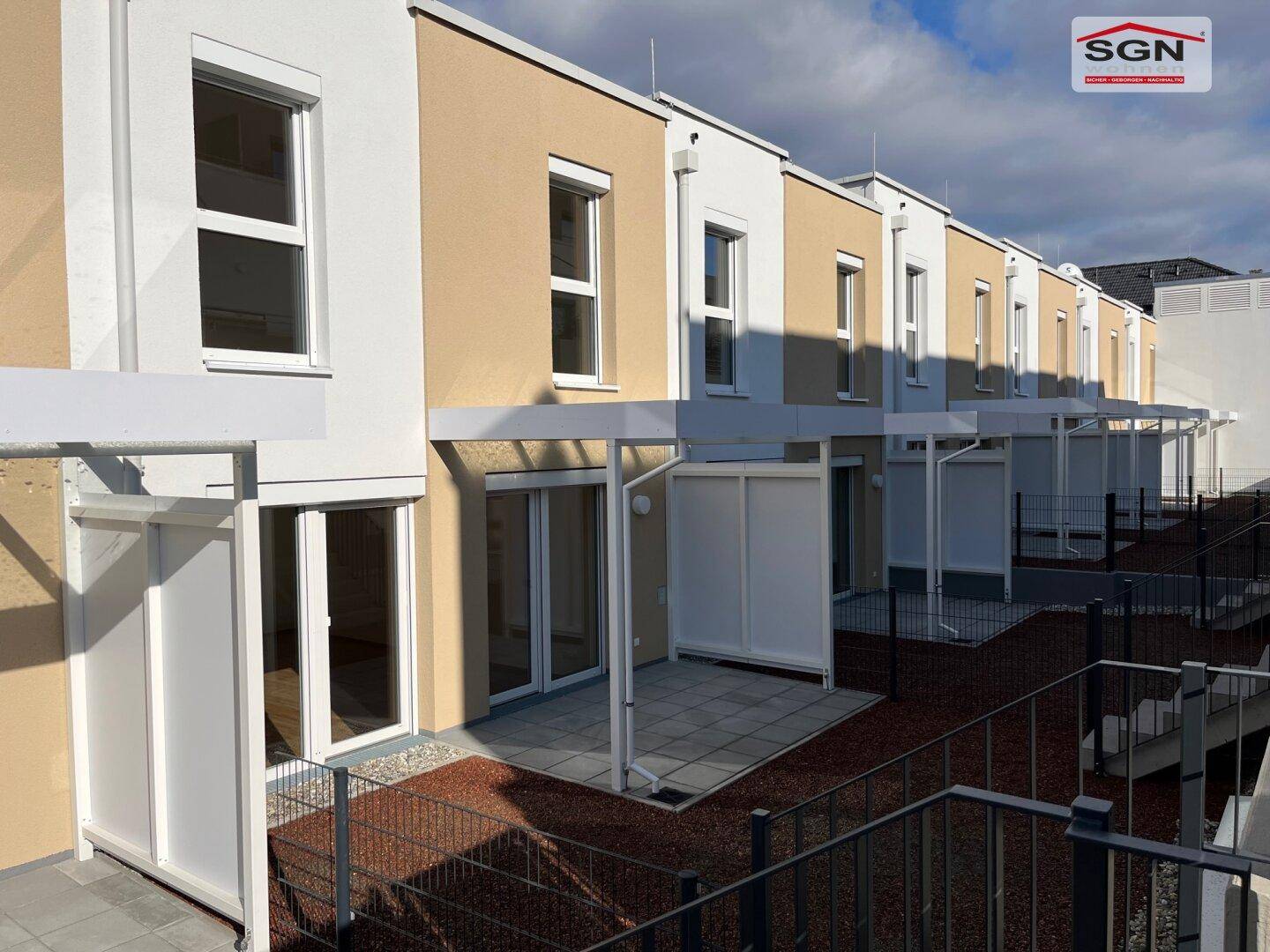 Rückansicht der Reihenhäuser mit privaten Terrassen und kleinen Gärten, bereit zur Gestaltung.