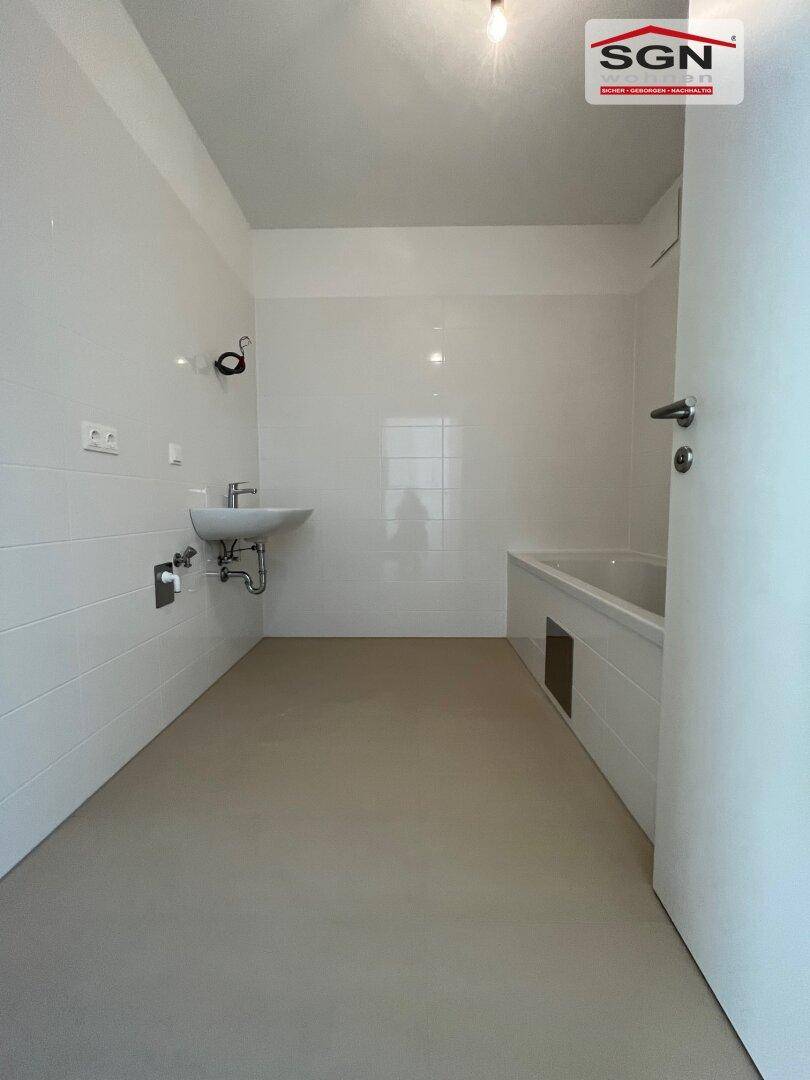 Modernes Badezimmer mit weißen Fliesen, Waschbecken und Badewanne, bereit für die Einrichtung.