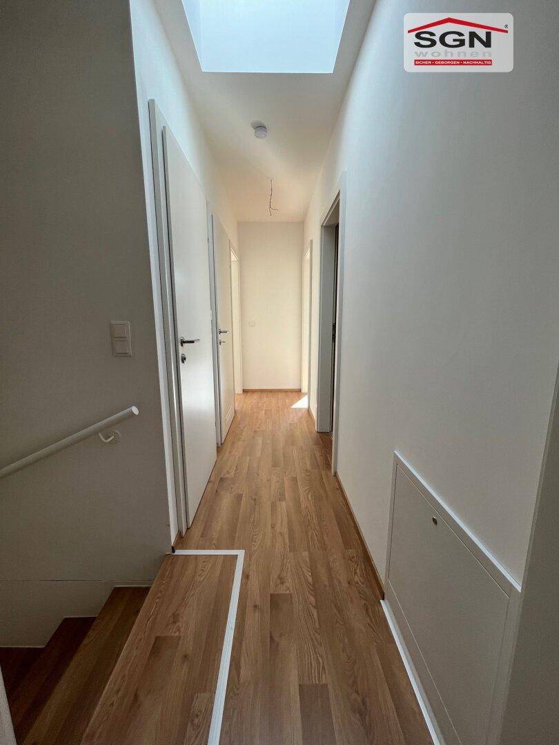 Lichtdurchfluteter Flur im Obergeschoss mit Laminatboden und Oberlicht, der zu den Zimmern führt.