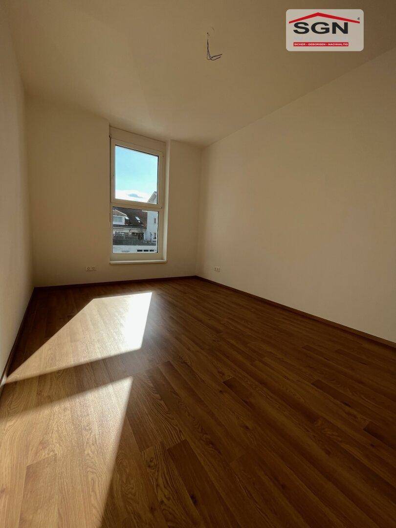 Geräumiges, unmöbliertes Zimmer mit Laminatboden und heller Wandfarbe, ideal für Schlaf- oder Wohnbereich.