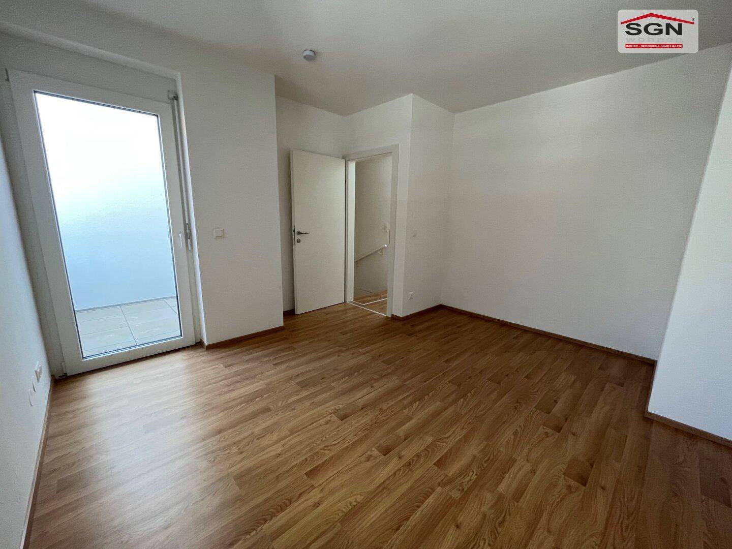 Heller Wohnraum mit Laminatboden und Zugang zu einem Außenbereich, ideal für gemütliche Stunden.