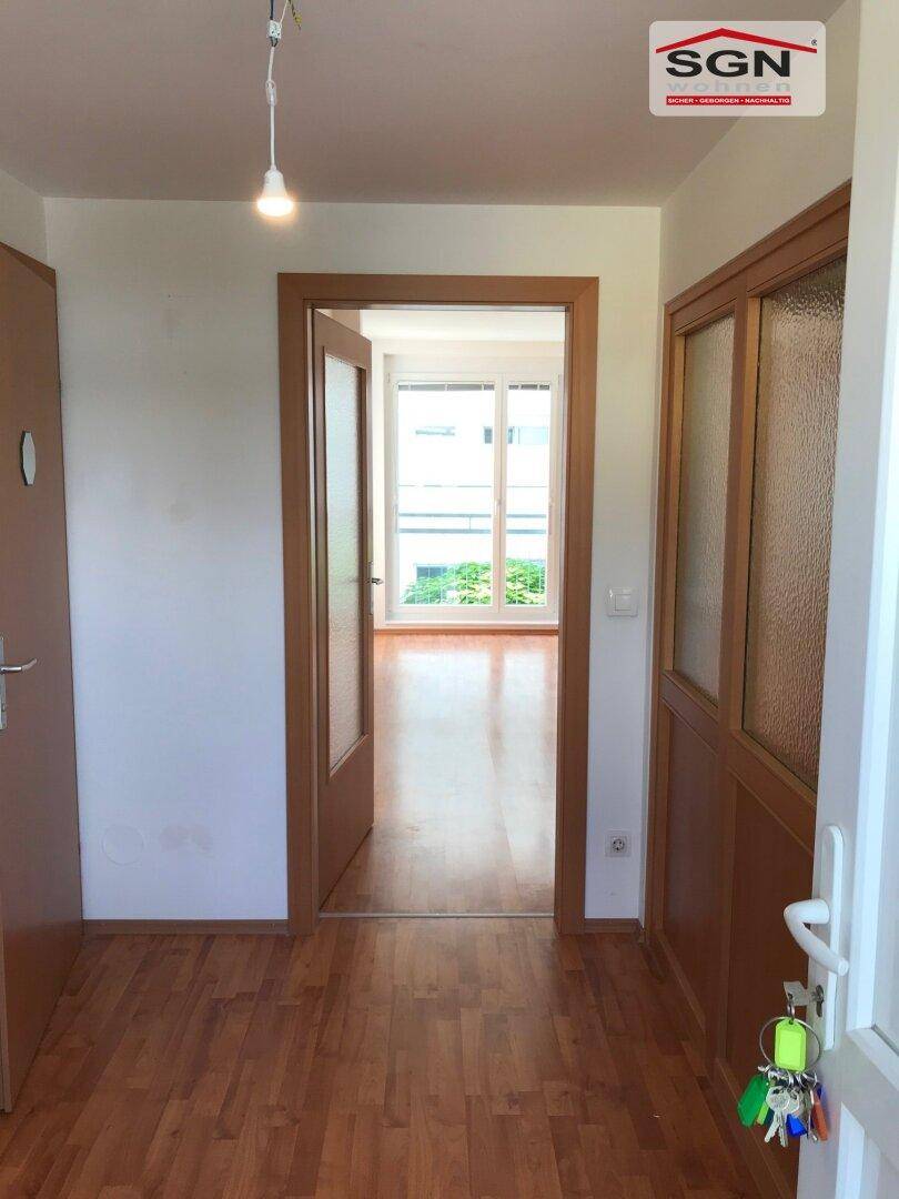 Heller Flur mit Laminatboden und Holztüren, der in einen weiteren Raum führt.