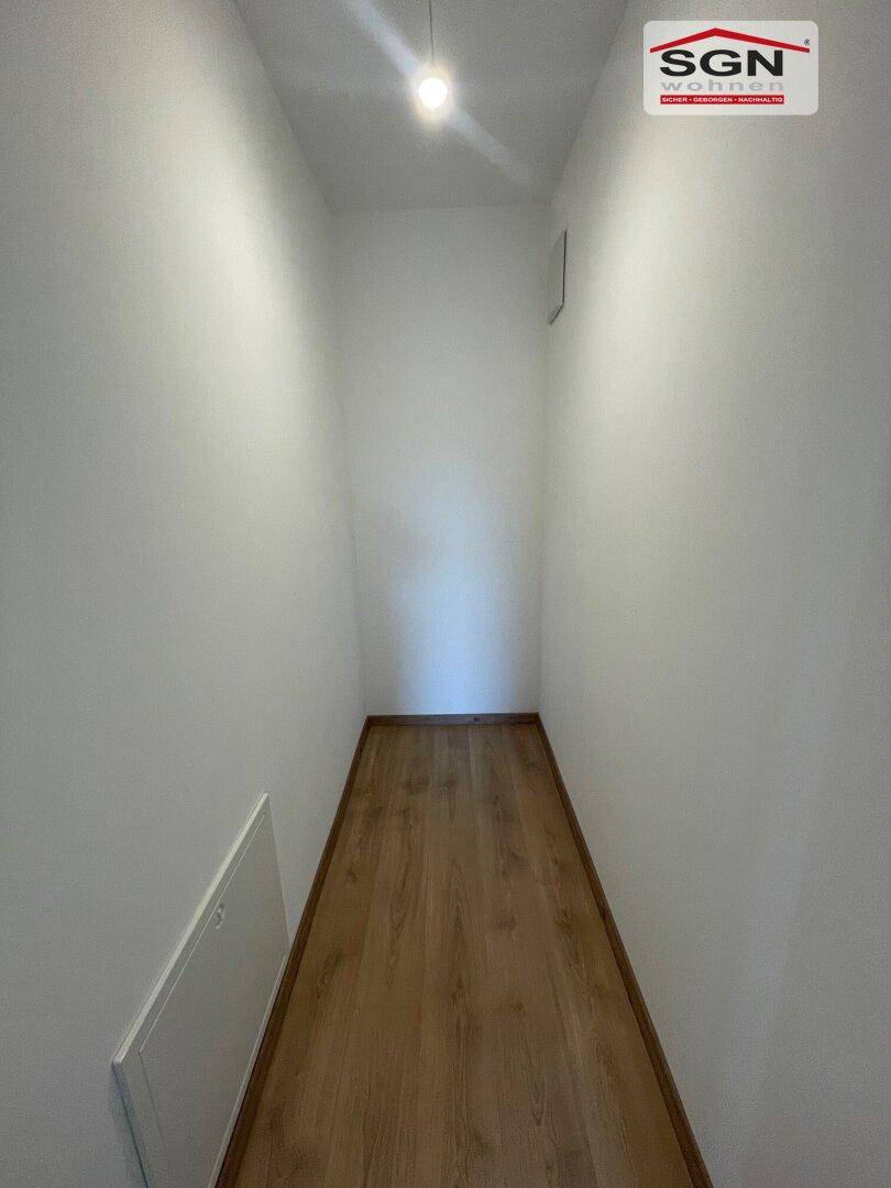 Schmaler Flur mit hellem Laminatboden und weißen Wänden.