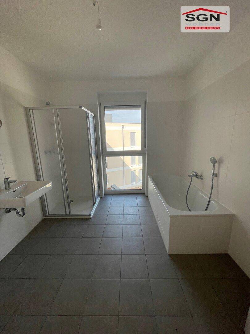 Geräumiges Badezimmer mit Badewanne, Duschkabine, Waschbecken und Fenster für Tageslicht.