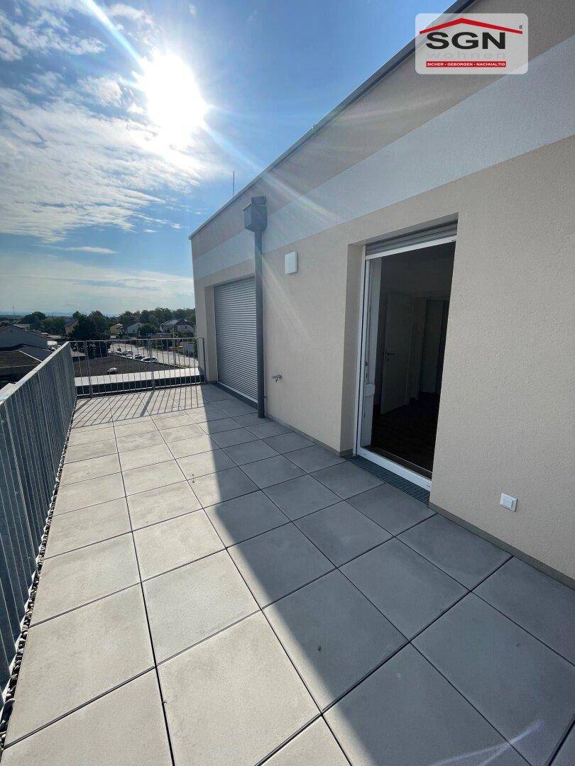 Sonnige Terrasse mit Fliesenboden und Schiebetürzugang zu den Wohnbereichen der Immobilie.