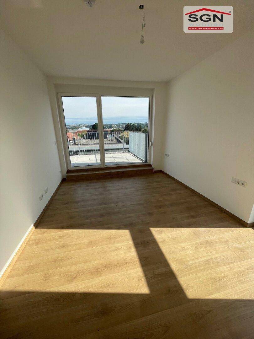 Großes Schlafzimmer mit Laminatboden und direktem Zugang zu einer privaten Terrasse mit Weitblick.