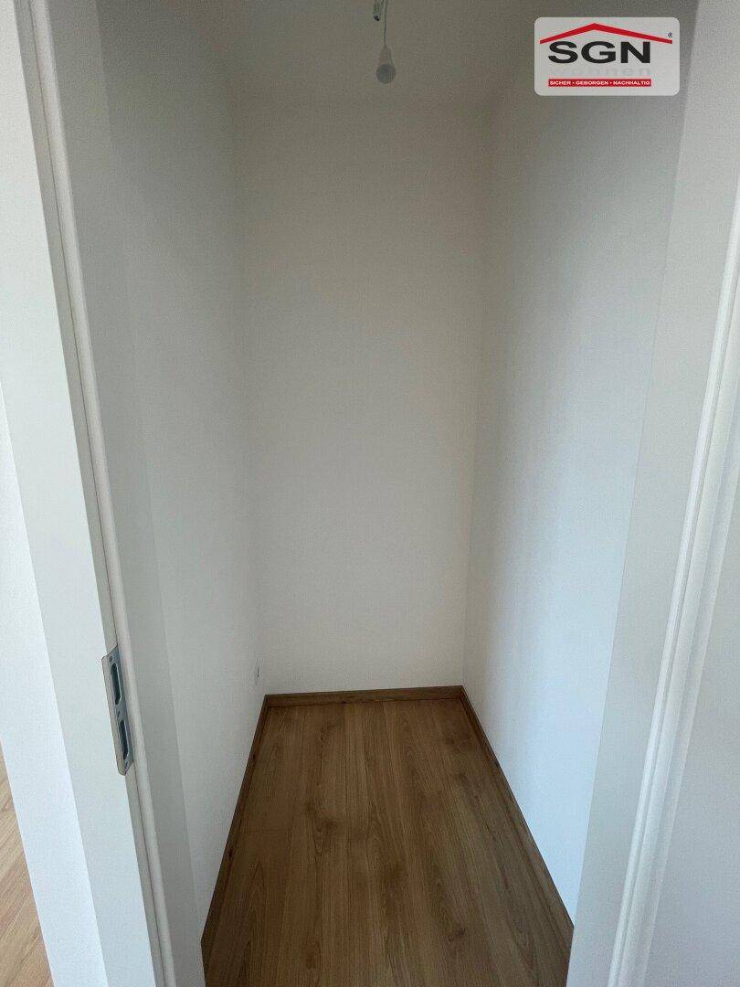 Kleiner Abstellraum mit Laminatboden und weißen Wänden, perfekt für Haushaltsutensilien.